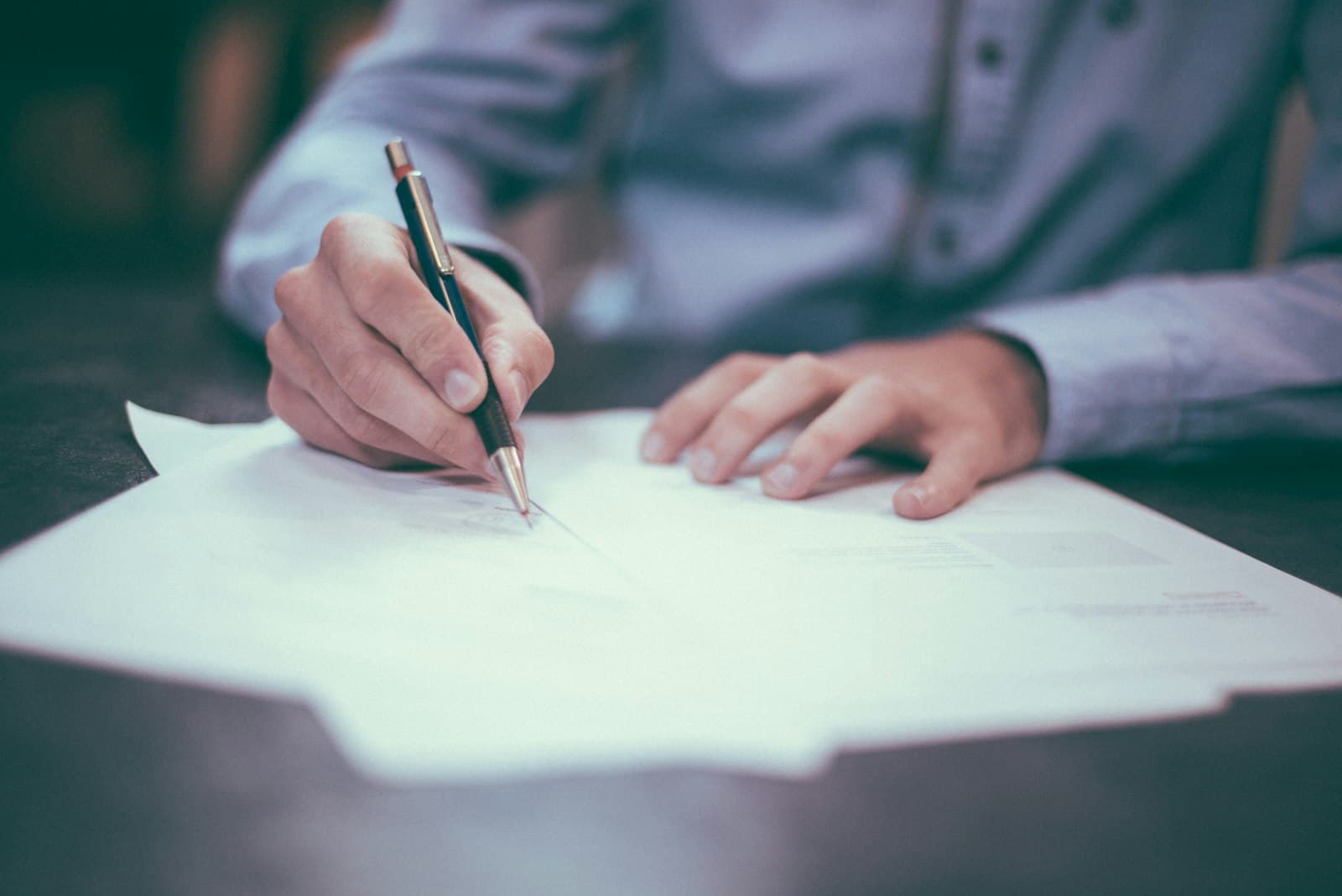A person signing documents at a desk, suggesting careful, considered care.
