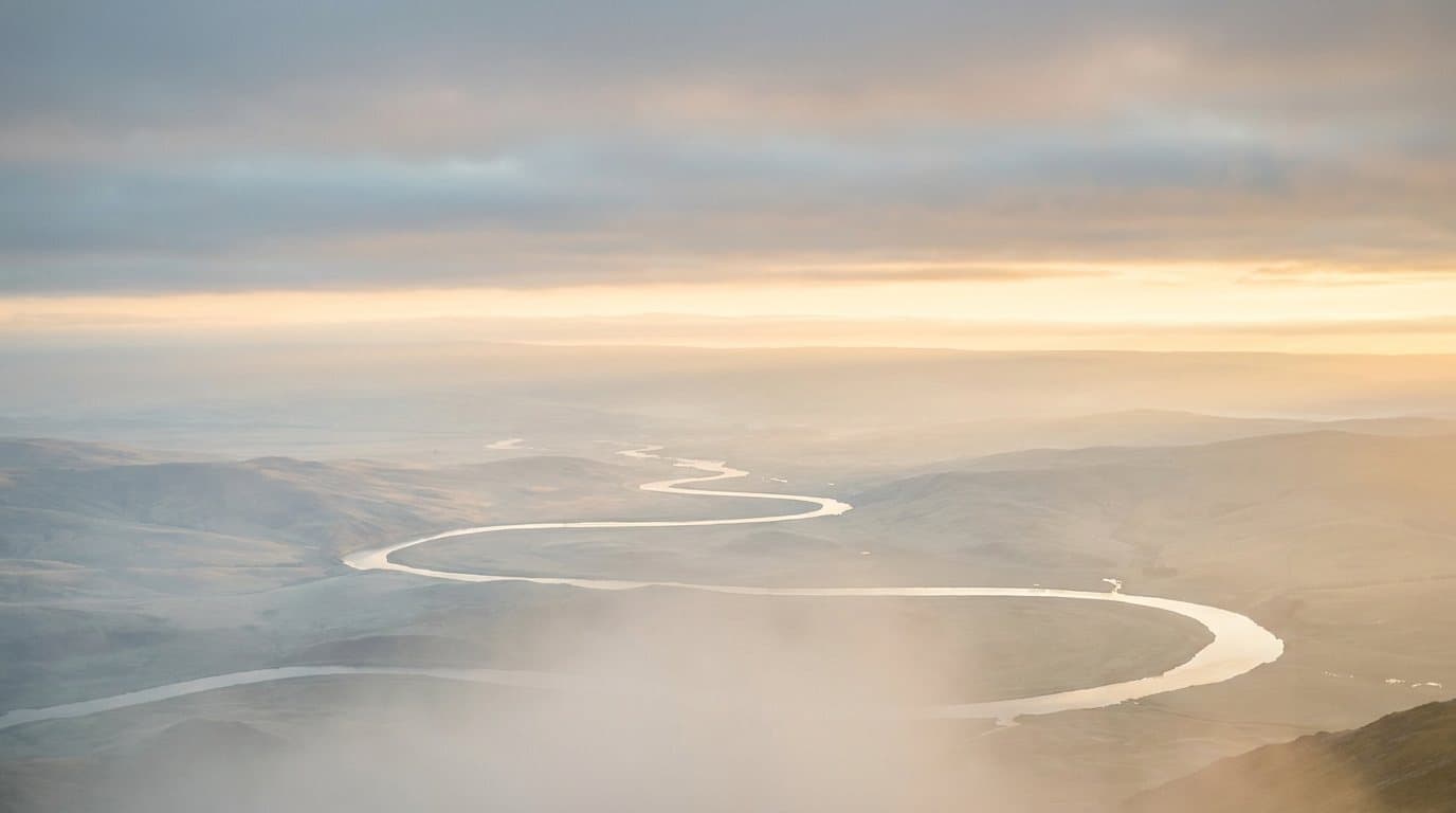 An open valley and winding path under golden dawn light.
