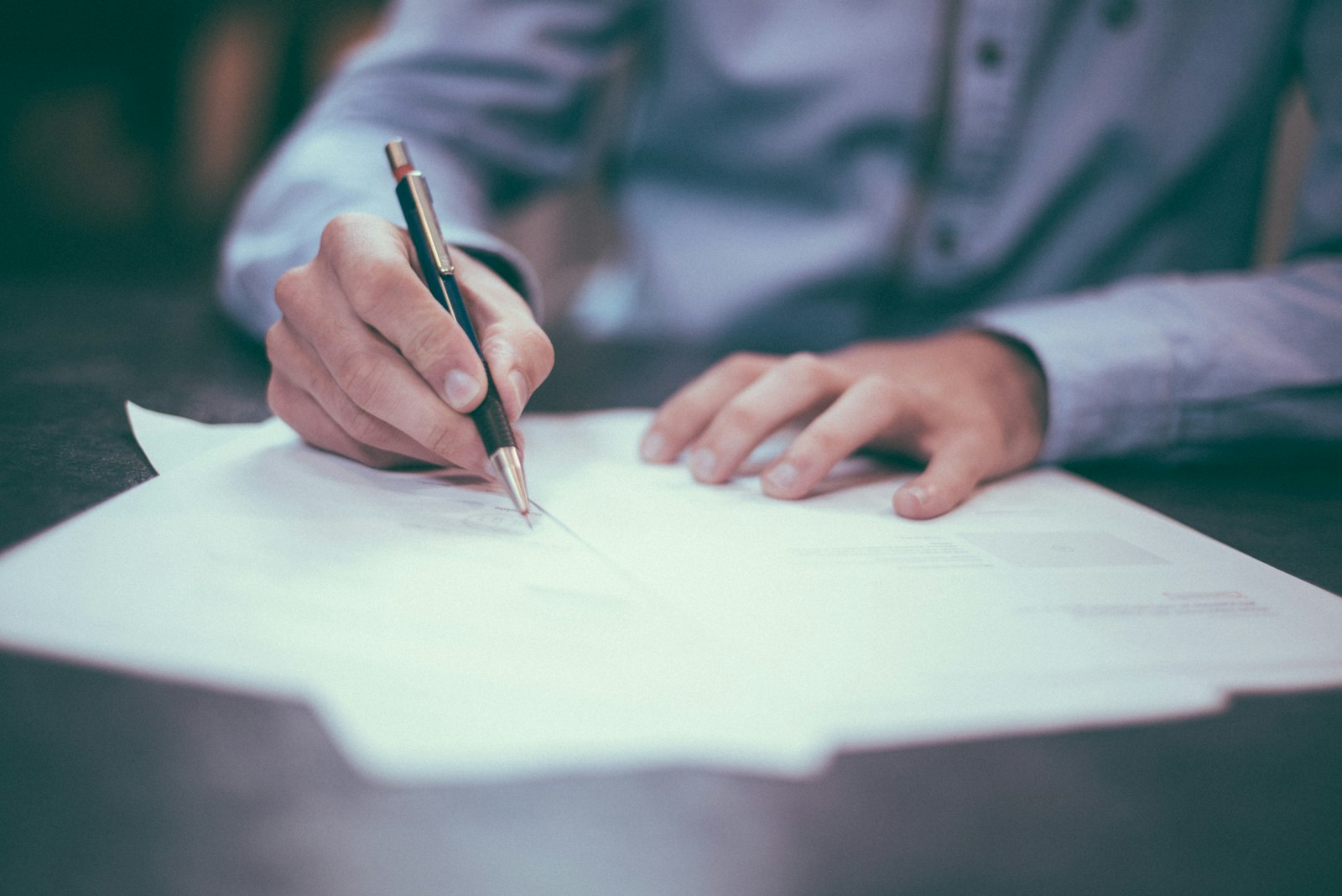 A person signing documents at a desk, suggesting careful, considered care.