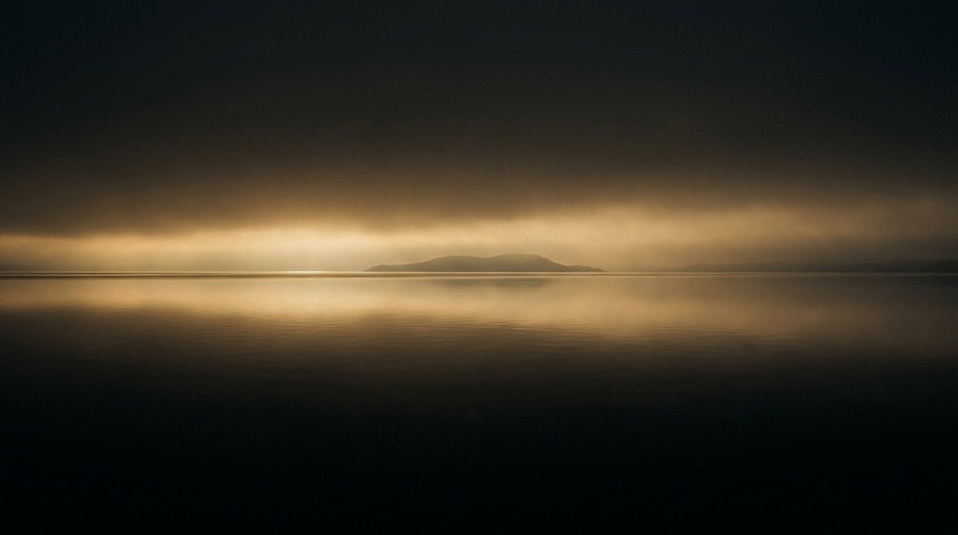 Still water under a wide band of gold dawn light.